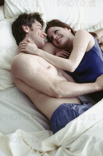 Young couple in bed. Photographe : Rob Lewine