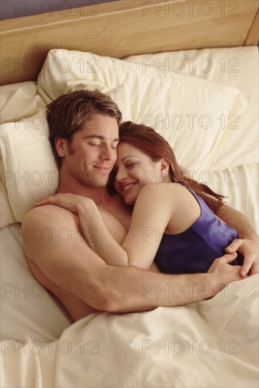 Young couple in bed. Photographe : Rob Lewine