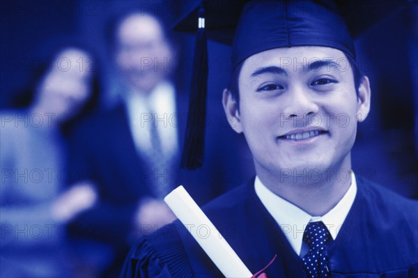 Graduate holding his diploma. Photographe : Rob Lewine