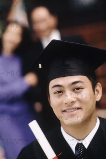 Graduate holding his diploma. Photographe : Rob Lewine