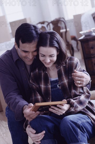 Couple looking at a framed photograph. Photographe : Rob Lewine