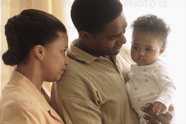 Portrait of parents with their baby. Photographe : Rob Lewine