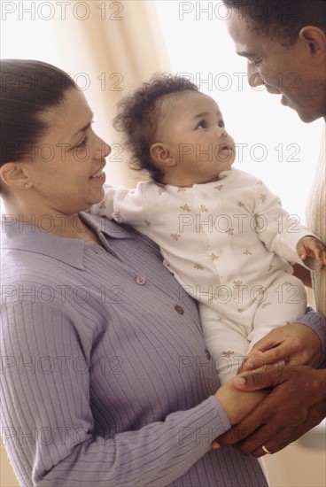 Mother and father holding their baby. Photographe : Rob Lewine