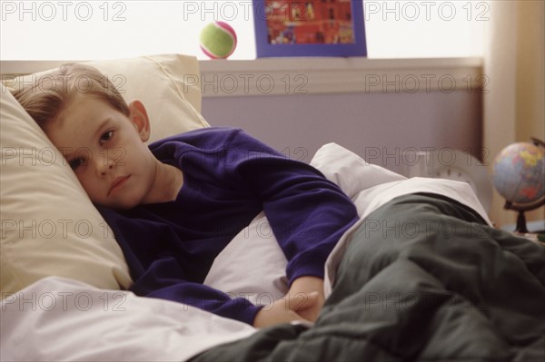 Young boy sick in bed. Photographe : Rob Lewine