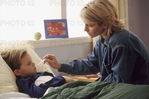 Mother checking son's temperature. Photographe : Rob Lewine