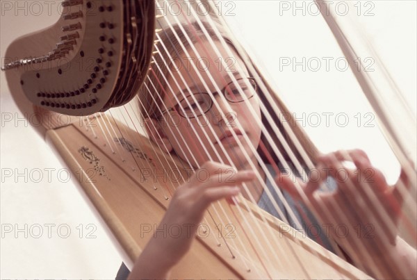 Young girl playing the harp. Photographe : Rob Lewine