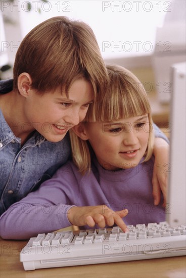 Siblings looking at computer together. Photographe : Rob Lewine