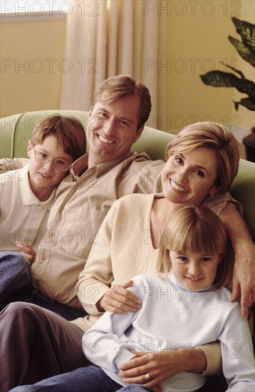 Family relaxing on couch together. Photographe : Rob Lewine