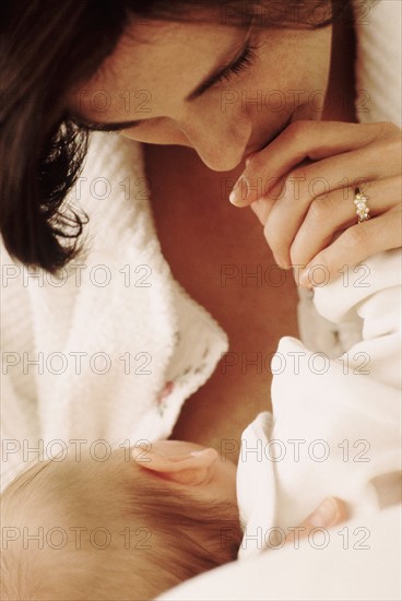 Mother kissing her babies hand. Photographe : Rob Lewine