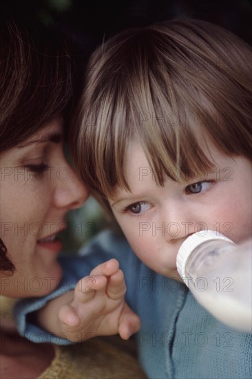 Mother giving her child a bottle. Photographe : Rob Lewine