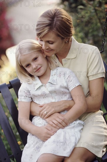 Mother and daughter embracing in the garden. Photographe : Rob Lewine