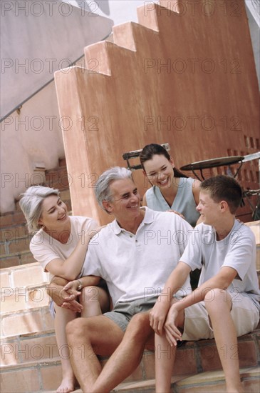 Family sitting on steps together. Photographe : Rob Lewine