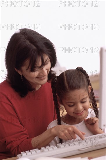 Mother teaching daughter how to use the computer. Photographe : Rob Lewine