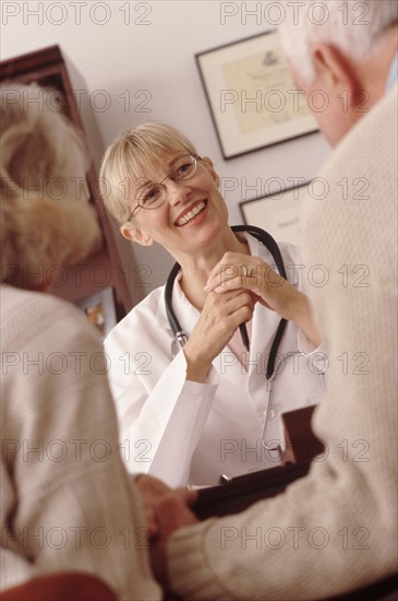 Elderly couple talking to doctor. Photographe : Rob Lewine