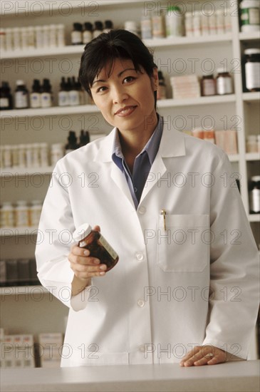 Pharmacist holding a bottle of prescription medication. Photographe : Rob Lewine