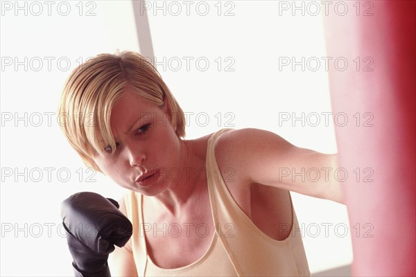 Woman using a punching bag. Photographe : Rob Lewine