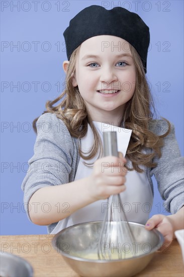 Young girl mixing with a whisk. Photographe : Dan Bannister