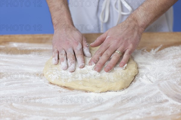 Man's hands kneading bread dough. Photographe : Dan Bannister