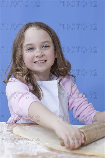 Young girl rolling out bread dough. Photographe : Dan Bannister