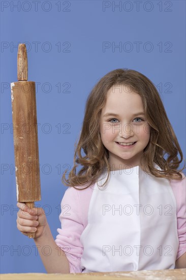 Young girl holding a rolling pin. Photographe : Dan Bannister