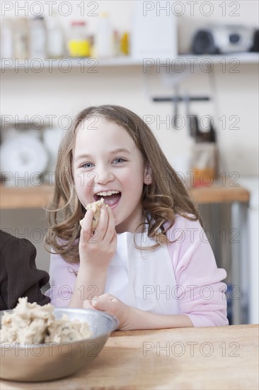 Young girl eating cookie batter. Photographe : Dan Bannister