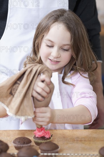 Young girl decorating cupcakes. Photographe : Dan Bannister