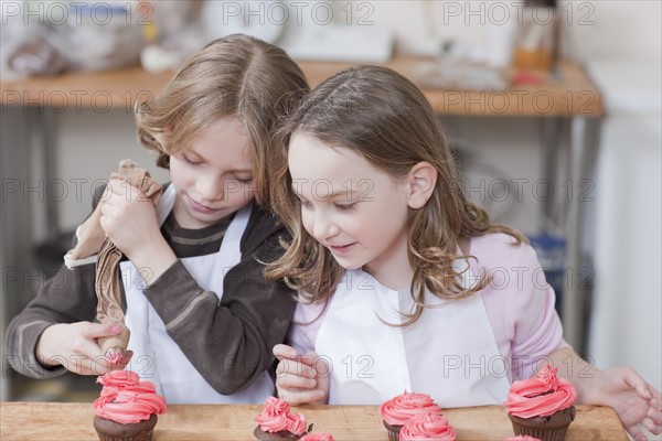 Young girls decorating cupcakes. Photographe : Dan Bannister