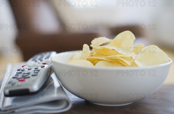 Bowl of chips beside remote control.