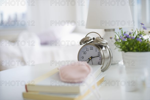 Sleep mask books and alarm clock on bedside table.