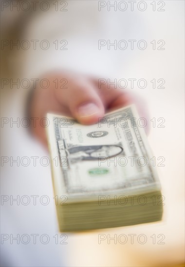 Hand holding stack of money.