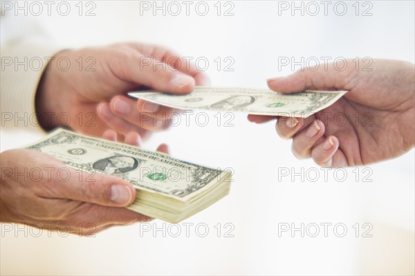 Hands passing dollar bill.