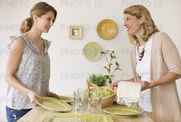 Mother and daughter setting the table.