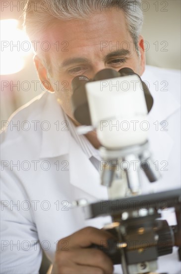 Researcher looking through microscope.