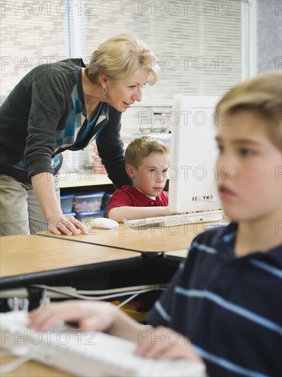 Teacher helping young student in computer lab.