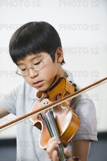 Elementary school student playing violin in music class.