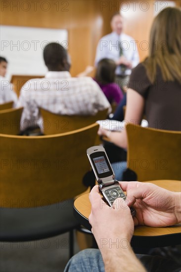 College student texting in lecture hall.