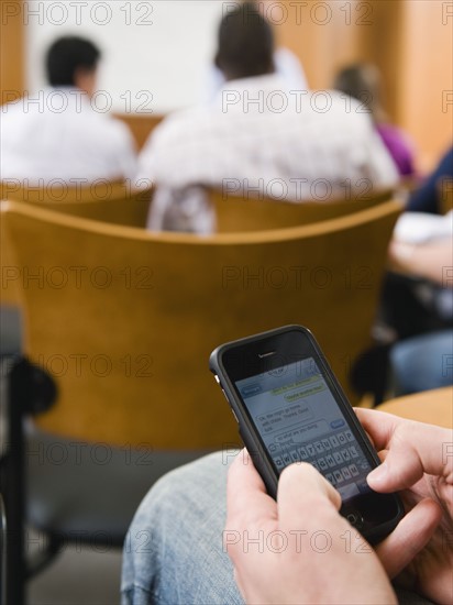 College student texting in lecture hall.