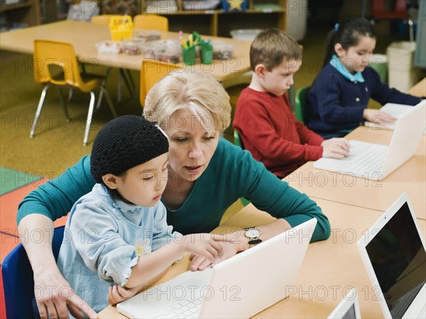 Teacher and kindergarten student looking at laptop.