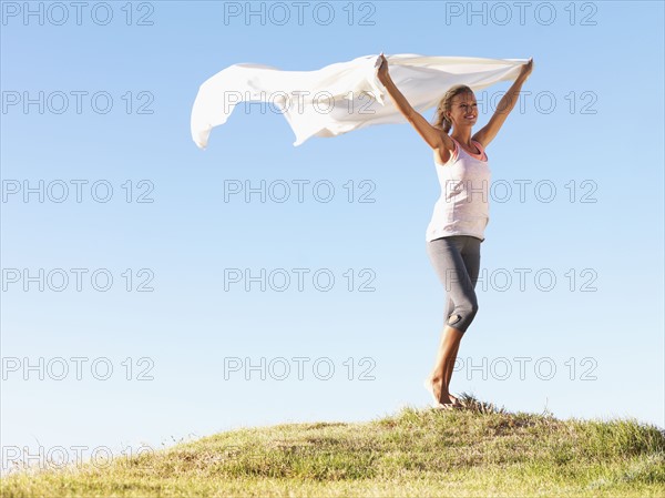 Woman holding a white scarf over her head. Photo : momentimages