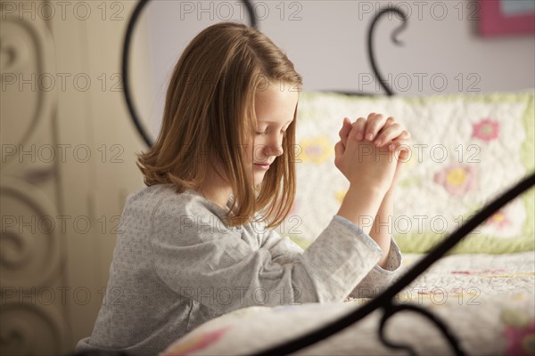 Young girl praying before bed. Photo : Mike Kemp