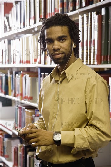 Man listening to music with headphones in library. Photo : Stewart Cohen