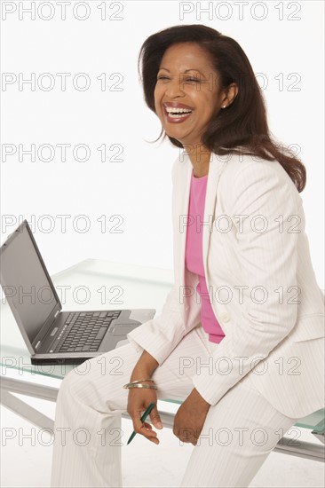 Happy businesswoman sitting on desk. Photo : K.Hatt