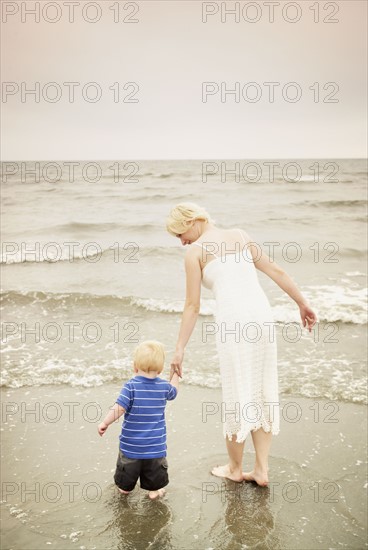 Mother and child walking hand in hand at the water's edge. Photo : Shawn O'Connor