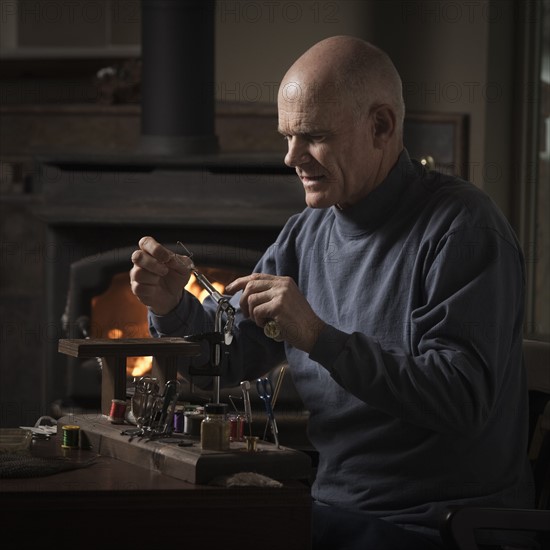 Man working on fly fishing hook. Photo : Mike Kemp