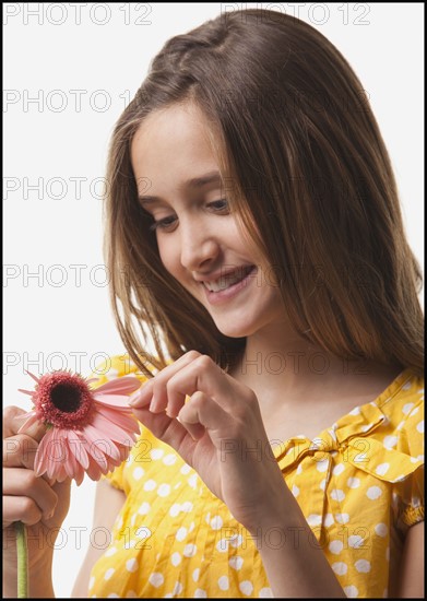 Teenage girl picking petals off of a flower. Photo : Mike Kemp