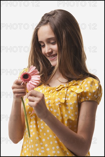 Teenage girls picking petals off of a flower. Photo : Mike Kemp