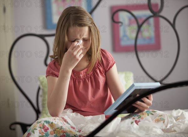 Young girl crying while looking at photograph. Photo : Mike Kemp