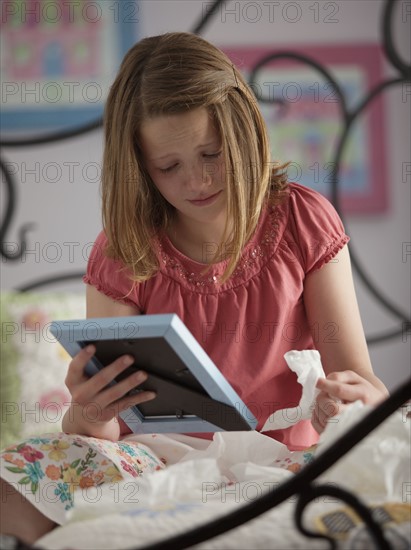 Young girl crying while looking at photograph. Photo : Mike Kemp