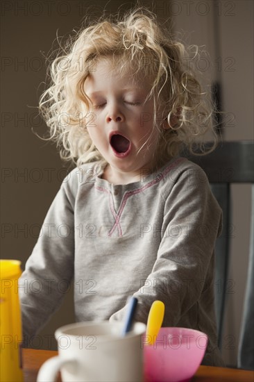 Yawning child at the breakfast table. Photo : Mike Kemp