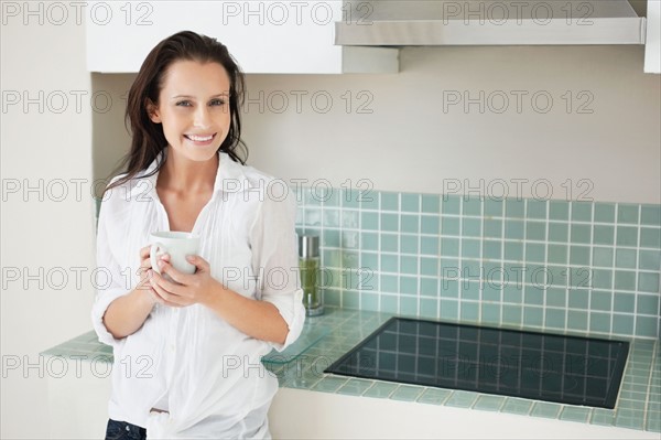 Woman drinking coffee in kitchen. Photo : momentimages